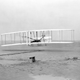 Orville Wright, lying at the controls on the lower wing, pilots the Wright Flyer on the first powered flight by a heavier-than-air aircraft, Dec. 17, 1903, at Kitty Hawk, N.C